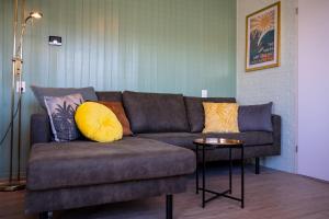 un sofá con almohadas en la sala de estar en iwalani Beach Bungalow - large Private Garden - close to City Center & Beach en De Koog