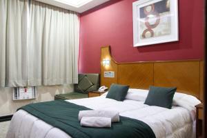 a bedroom with a large bed and a red wall at Capri Hotel in Duque de Caxias