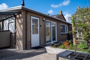 a brick house with a white door at iwalani Beach Bungalow - large Private Garden - close to City Center & Beach in De Koog +18 photos
