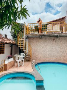 una donna in piedi su un balcone accanto alla piscina di Pousada dos Candeeiros a Carolina