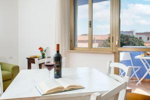 un tavolo con un libro e un bicchiere di vino di Appartamenti Lungoni a Santa Teresa di Gallura