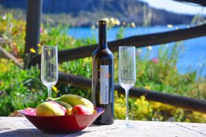 a bowl of apples and a bottle of wine and two glasses at Coral Front Beach in Kato Zakros