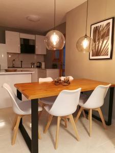 - une cuisine avec une table en bois et des chaises blanches dans l'établissement Naufragos Apartament Torrevieja, à Torrevieja