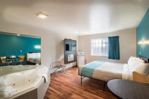 Motel 6-Rigby, ID في Lorenzo: غرفة الفندق بسرير كبير وحوض استحمام