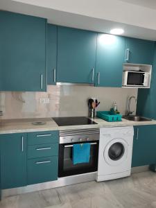 a kitchen with blue cabinets and a washing machine at Apartamento con wifi, mascotas bienvenidas in Benidorm