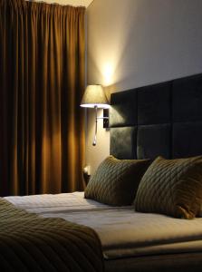 - une chambre avec un lit doté d'une tête de lit noire et d'une lampe dans l'établissement Senoji užeiga, à Moletai