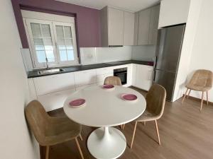 una piccola cucina con tavolo e sedie bianchi di Alojamientos con encanto Ruliña a Portomarin