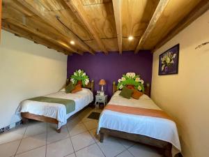 two beds in a room with purple walls and wooden ceilings at Hotel Hacienda Encantada in Real de Catorce