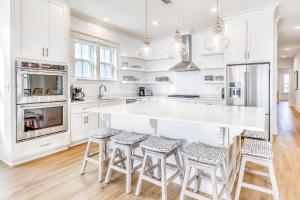 a kitchen with white cabinets and a large island with stools at Beach Vista Two in Orange Beach
