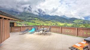 a balcony with a table and chairs and mountains at Apartments Fiechtl in Leogang