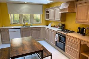 a kitchen with wooden cabinets and a stove top oven at Lynwood - Victorian Home in the Peak District in Bakewell