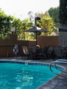 einen Pool mit Stühlen, Tischen und einem Sonnenschirm in der Unterkunft GreenTree Inn & Suites Los Angeles - Alhambra - Pasadena in Alhambra