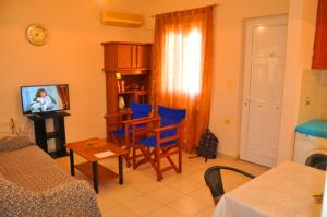 a living room with blue chairs and a television at Dimitra Apartments Zakros in Kato Zakros