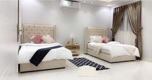 2 camas en un dormitorio con paredes blancas y almohadas rosas en مساكن الدار 1 en Abha