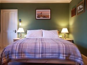 a bedroom with a large bed with a plaid blanket at Afallon Townhouse Salop Room in Dolgellau