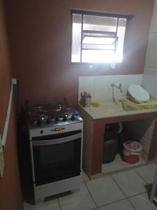 a kitchen with a stove and a counter with a sink at Pousada Ypê das Montanhas in Monte Alegre do Sul