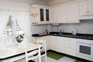 a kitchen with white cabinets and a table and chairs at Apartamento Sol do Coído in Muxia