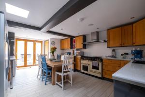 a kitchen with wooden cabinets and a table and chairs at Central Penzance, Modern stylish home, Near Seafront with Gated parking in Penzance