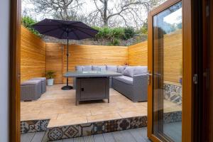 a patio with a table and a couch and an umbrella at Central Penzance, Modern stylish home, Near Seafront with Gated parking in Penzance