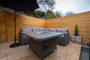 a patio with a table and chairs and an umbrella at Central Penzance, Modern stylish home, Near Seafront with Gated parking in Penzance +32 photos
