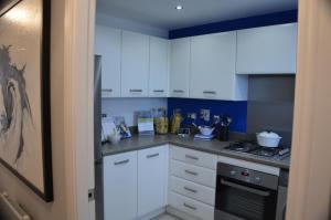 a kitchen with white cabinets and a stove top oven at Hollygate Cottage in Cotgrave