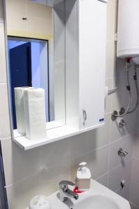 La salle de bains est pourvue d'un lavabo blanc et d'un miroir. dans l'établissement Sweet Home Vrnjačka Banja, à Vrnjačka Banja