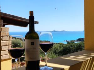 a bottle of wine sitting next to two glasses of wine at VILLA CLAUDIO e LUNETTA in Villasimius
