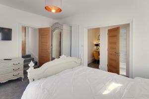 a white bedroom with a white bed and a dresser at Master accommodation suite 2 sea view with balcony in Hastings