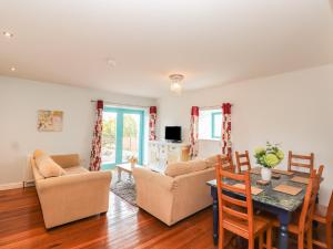 a living room with a table and a dining room at Badger Cottage in Dalbeattie