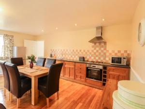 a kitchen with a wooden table and black chairs at Hereford Cottage in Dalbeattie