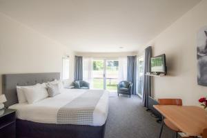 una camera d'albergo con un grande letto e una scrivania di Lake Dunstan Motel a Cromwell