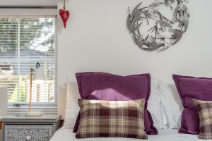 a bed with purple pillows and a clock on the wall at Redlands Country Lodge Apartments with Hot Tubs in Ladybank