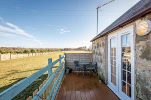 a deck with a table and chairs on a house at Redlands Country Lodge Apartments with Hot Tubs in Ladybank