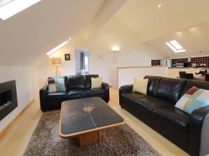 a living room with two leather couches and a coffee table at Cholwell Barn Apartment in Tavistock