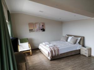 een slaapkamer met een bed, een stoel en een televisie bij LUX Apartman in Balatonfüred