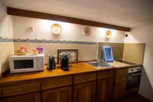 a kitchen counter with a microwave and a sink at Casa do Campanário in Sortelha