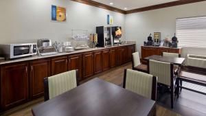 kuchnia ze stołami, krzesłami i kuchenką mikrofalową w obiekcie Best Western Inn & Suites w mieście Byron