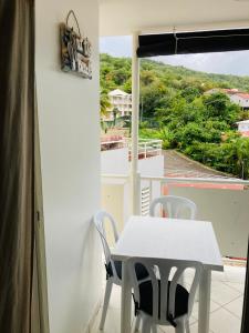 einen weißen Tisch und Stühle auf einem Balkon mit Aussicht in der Unterkunft Studio Ana Martinique in La Trinité