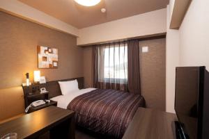 a hotel room with a bed and a desk at Hotel Route-Inn Higashihiroshima Saijo Ekimae in Higashihiroshima
