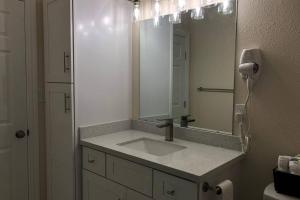 a bathroom with a sink and a mirror at Seaside Cottage in Galveston