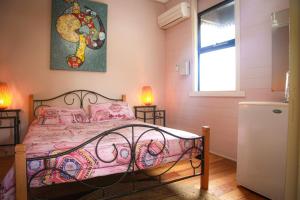 a bedroom with a bed with pink sheets and a window at Dreamtime Hostel in Cairns