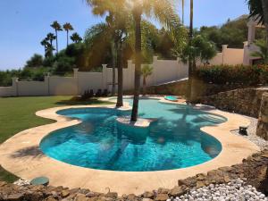 a pool with a palm tree in a yard at Huge Golf and Spa Mansion 8 min from Puerto Banus in Estepona
