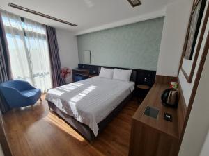 ein Hotelzimmer mit einem Bett und einem blauen Stuhl in der Unterkunft Ngan Hoa - Mille Fleurs 02 in Da Lat