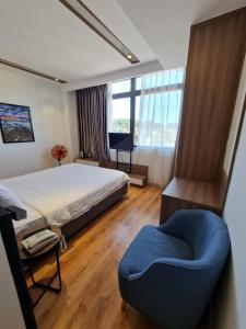 ein Schlafzimmer mit einem großen Bett und einem blauen Stuhl in der Unterkunft Ngan Hoa - Mille Fleurs 02 in Da Lat