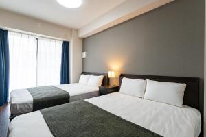 a hotel room with two beds and a window at Hotel Piacere NAMBA in Osaka
