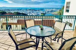 a table and chairs on a balcony with a harbor at Tropical Oasis, Million Dollar Views, 2 Pools in Cannonvale
