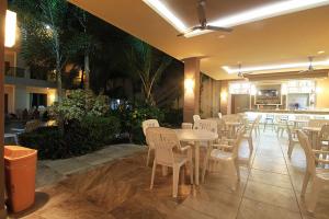 a restaurant with white tables and chairs and a bar at Rincon Resort in Los Ayala