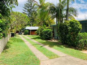 a sidewalk in front of a yard with palm trees at Koala Lodge Unit 3 in Iluka