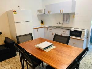 eine Küche mit einem Holztisch mit Stühlen und einem Kühlschrank in der Unterkunft Koala Lodge Unit 3 in Iluka