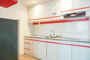 a kitchen with white cabinets and a sink at Cozy Living 1BR at Pakubuwono Terrace Apartment By Travelio in Jakarta